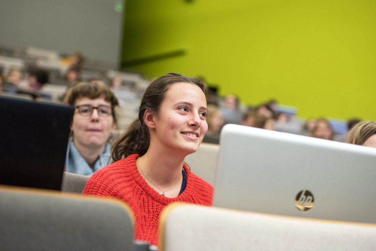 People listening and working on laptops during a public lecture or workshop.